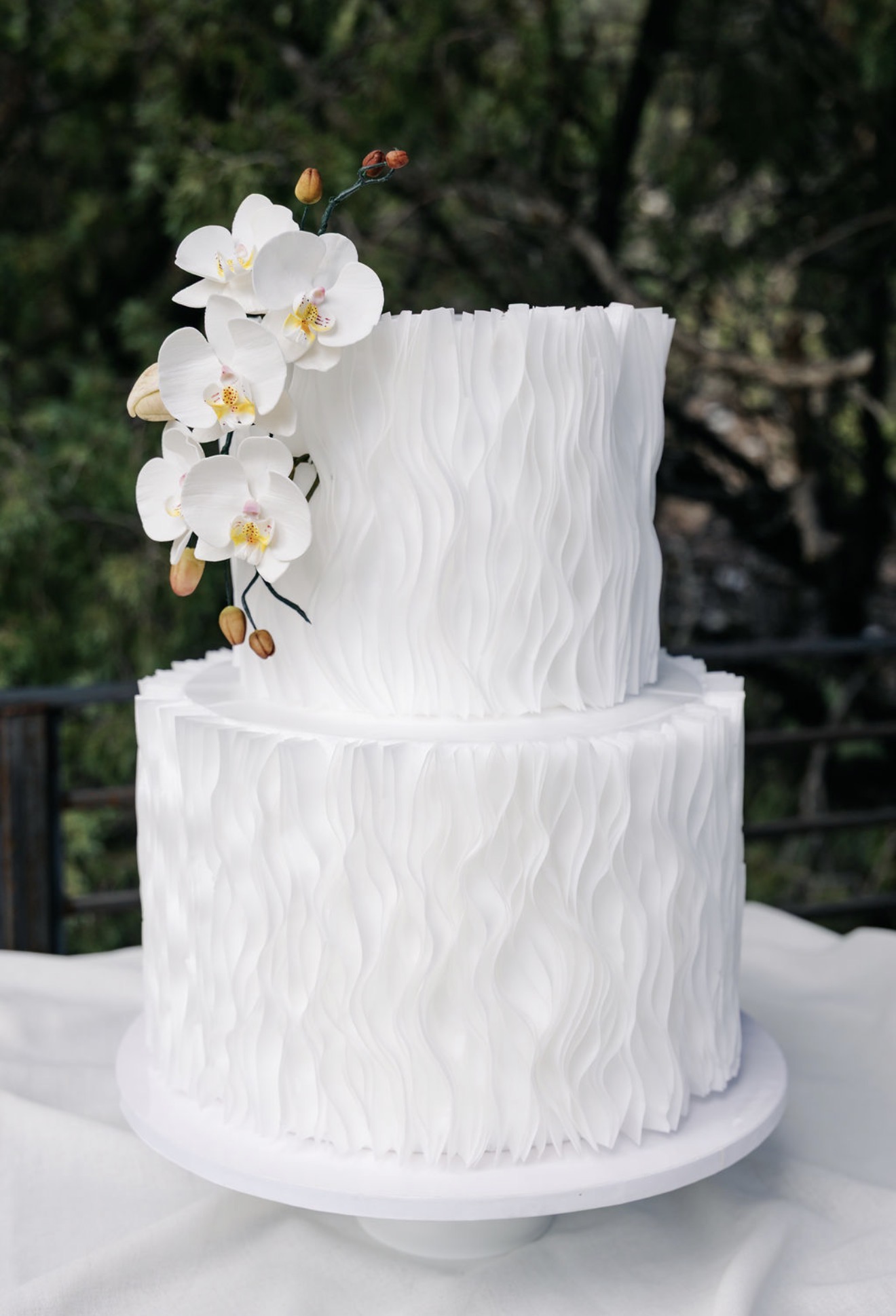 Two-tier wave-textured wedding cake with white sugar orchids