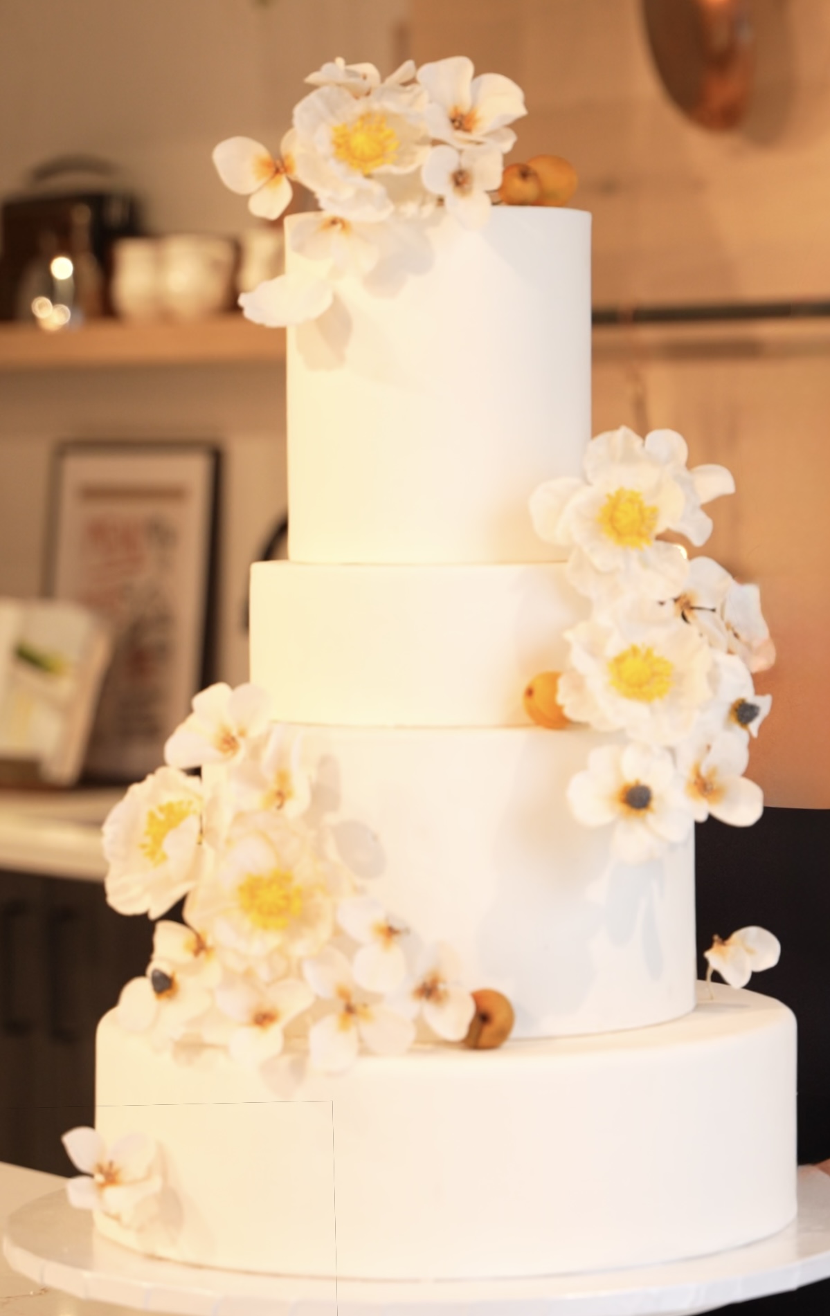 Four-tier white wedding cake with cascading sugar anemones and poppies