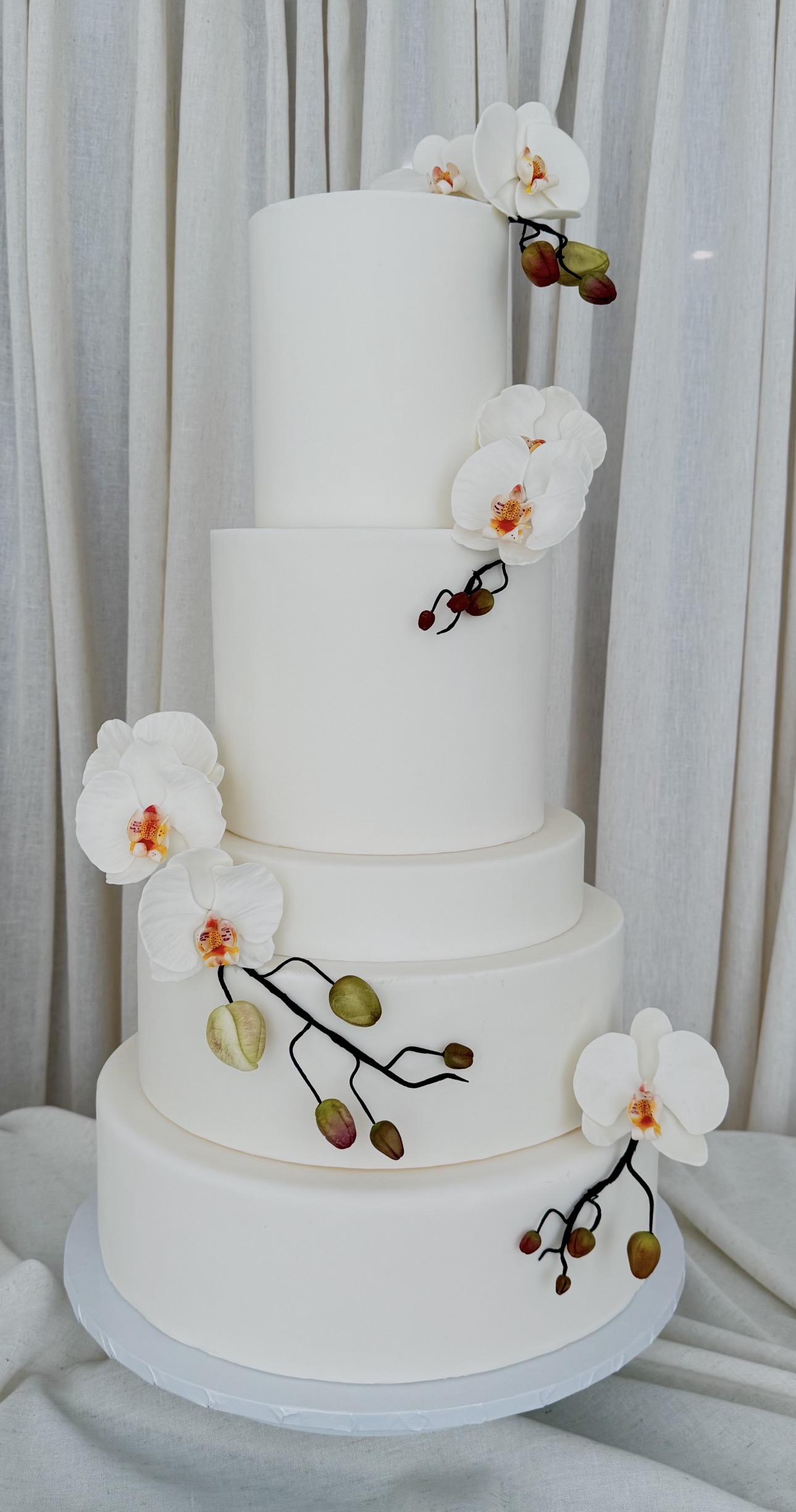 Five-tier white wedding cake with sugar phalaenopsis orchids and bud branches