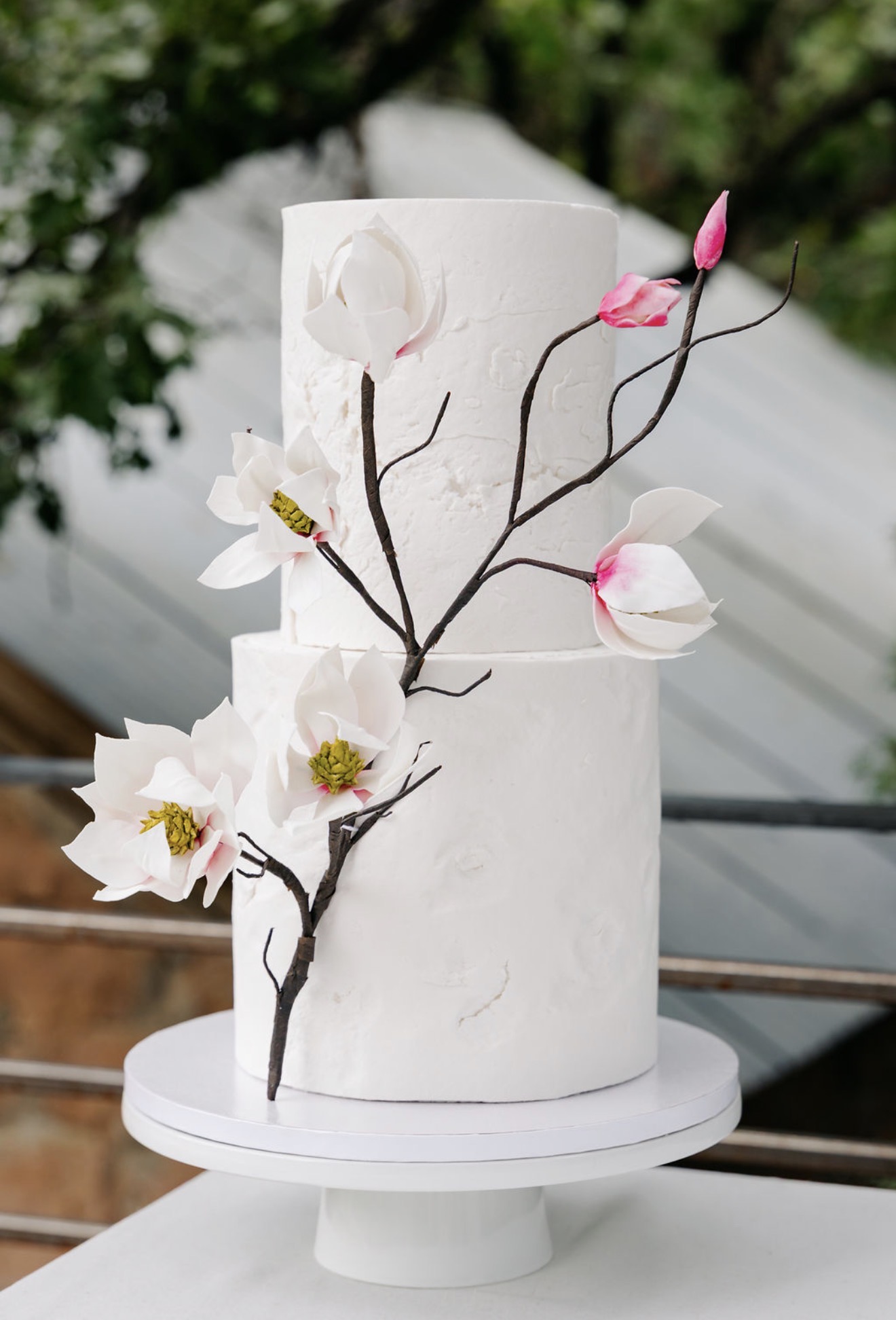 Two-tier textured wedding cake with a sugar magnolia branch