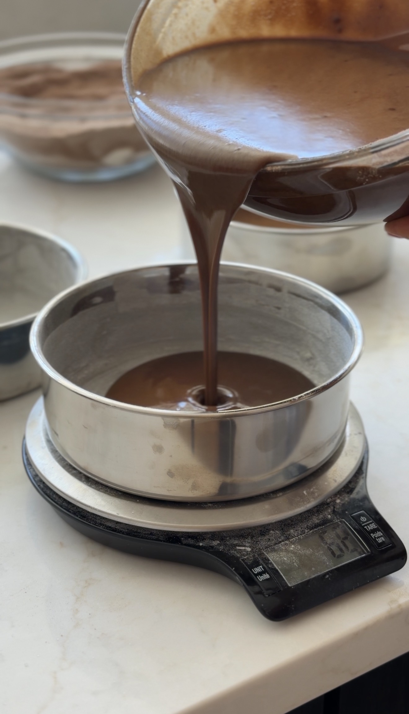 Chocolate cake batter being poured and weighed on a scale in the studio