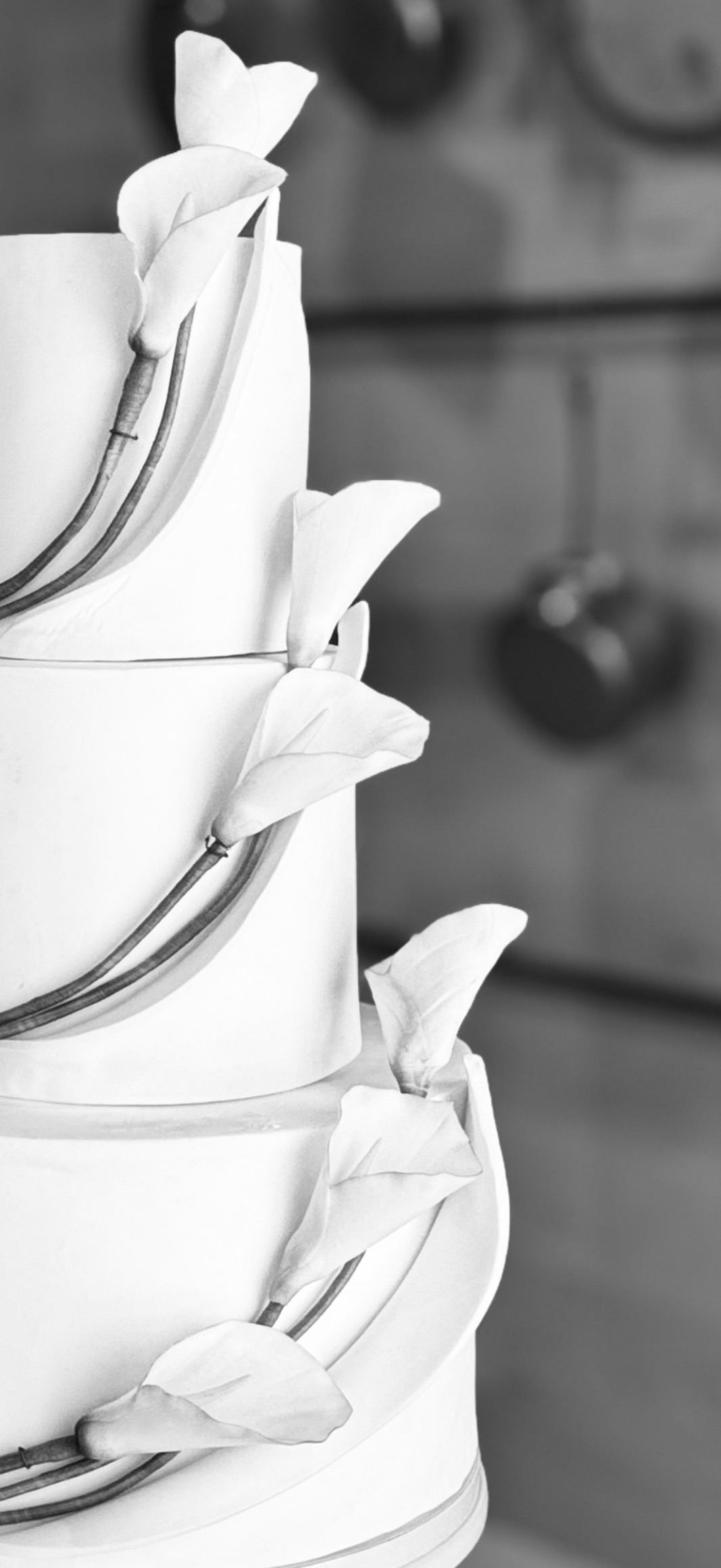 Black and white photograph of a tiered wedding cake with hand-sculpted sugar calla lilies